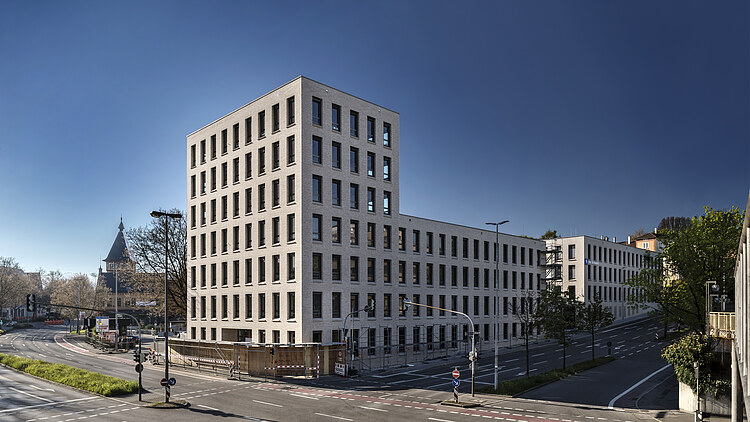 Foto von Gebäude von weiter weg mit Straße und blauem Himmel
