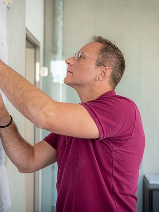Ein Mann bearbeitet einen Plan, der an die Wand gepinnt ist