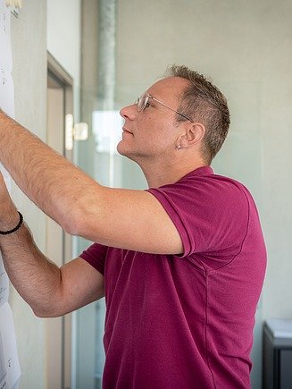 Ein Mann bearbeitet einen Plan, der an die Wand gepinnt ist