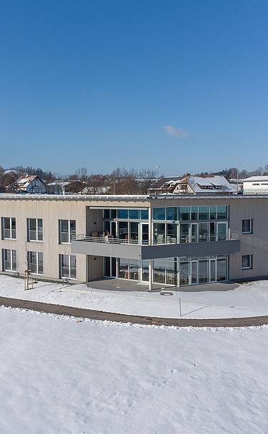 Foto von weit weg und oben mit Gebäudeecke und der Waldburg im Hintergrund