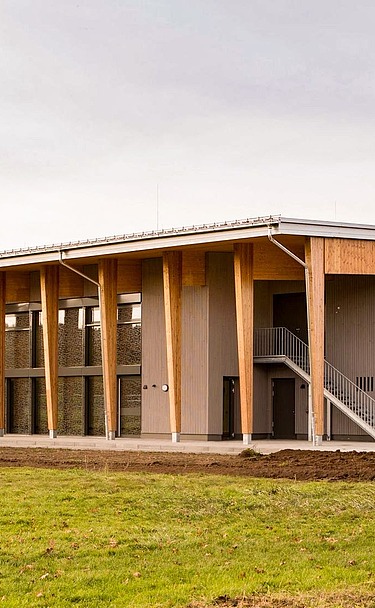 Foto Frontseite Sporthalle mit Sportplatz im Vordergrund