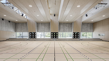 Foto Sporthalle Innen mit Holzdecke, Sichtbetonwänden und Sportboden