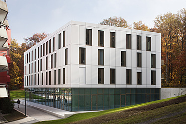 Foto von Gebäude mit weißer Fassade und Glaselementen im Erdgeschoss