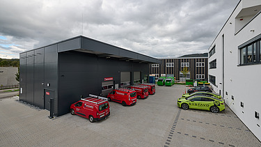 Foto auf die Lagerhalle hinter dem Bürogebäude mit Autos auf den Parkplätzen