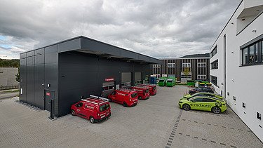 Foto auf die Lagerhalle hinter dem Bürogebäude mit Autos auf den Parkplätzen