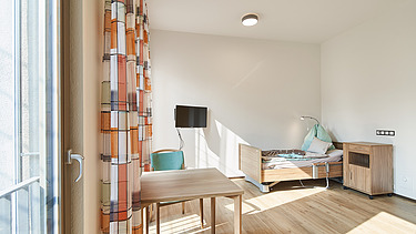 Foto Bewohnerzimmer mit Bett, Tisch und Fernseher