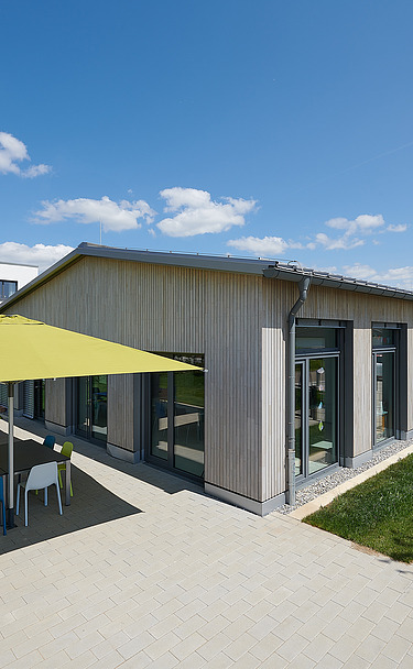 Foto Gebäude mit gepflasterter Terrasse und Sonnenschirmen