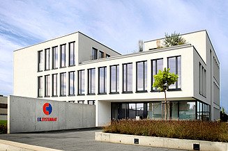 Foto von einem Verwaltungsgebäude mit weißer Fassade und Sichtbetonmauer