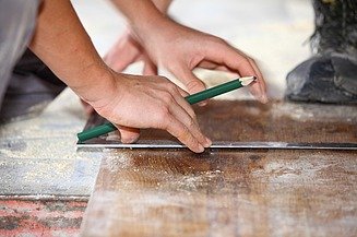 Foto von Händen, die mit Lineal und Bleistift auf einer Schaltafel etwas zeichnet