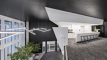 Foto mit Blick von oben auf Empfangsbereich mit offener Küche und Bar im 1. OG