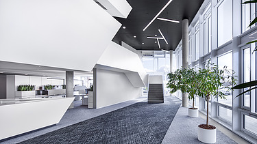 Foto Innenaufnahme Empfangsbereich mit dunklem Teppichboden und weißen Möbeln