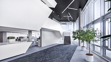 Foto Innenaufnahme Empfangsbereich mit dunklem Teppichboden und weißen Möbeln