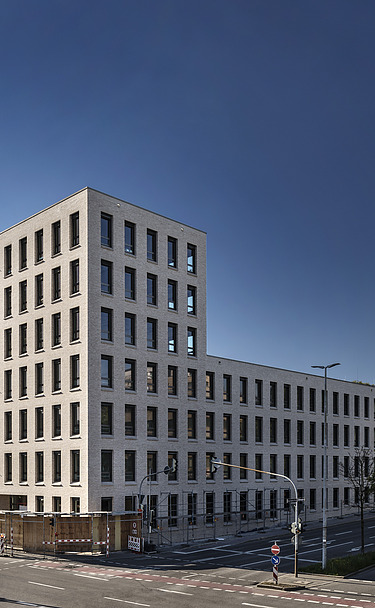 Foto von Gebäude von weiter weg mit Straße und blauem Himmel