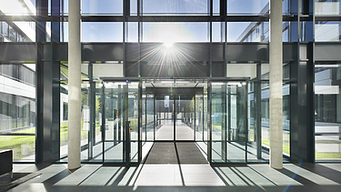 Foto Innenaufnahme vom Eingang mit viel Glas und Sonne