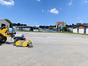 Asphaltierte Fläche mit Kehrmaschine im Vordergrund