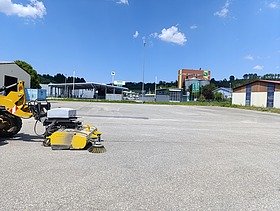 Asphaltierte Fläche mit Kehrmaschine im Vordergrund