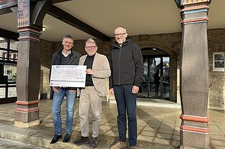 Foto von 3 Männern, die einen großen Spendenscheck in der Halt halten