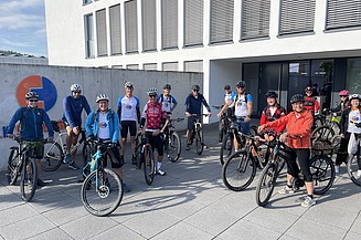 Foto von Menschen auf Fahrrädern vor einem Firmengebäde