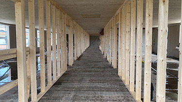 Foto eines Gang mit Sichtbeton und Holzständern