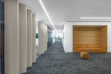 Foto eines Flurs mit dunklem Teppichboden und Sitznische mit Ledersofa