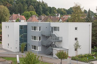 Foto von Gebäude von weiter weg mit Straße, Eingang 