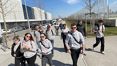 Foto von jungen Menschen, die nebeneinander laufen und gleiche Pullis an ttragen