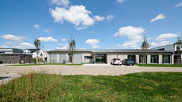 Foto von weiter weg auf Gesamtgebäude mit grüner Wiese und gepflastertem Weg