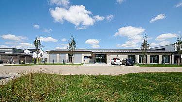 Foto von weiter weg auf Gesamtgebäude mit grüner Wiese und gepflastertem Weg