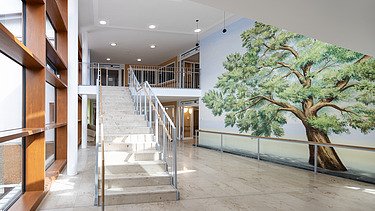 Foto im Innenbereich mit Steintreppe und bemalter Wand mit großem Baum