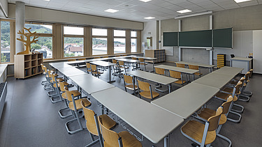 Foto Innenaufnahme Klassenzimmer mit Tischen, Stühlen und Tafel