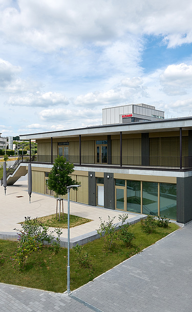 Foto Jugendzentrum von außen mit großem Vorplatz und Bahnschienen an der Seite