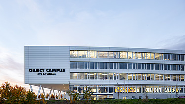 Foto Nahaufnahme mit Gebäudenamen und beleuchteten Büros