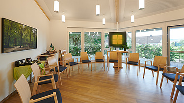 Foto eines Raum der Stille mit Stühlen und Fensterfront