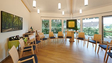 Foto eines Raum der Stille mit Stühlen und Fensterfront