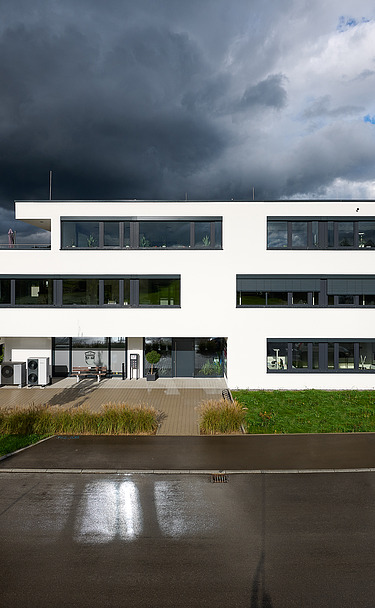 Foto des Gebäudes von der Straße aus mit Regenwolken