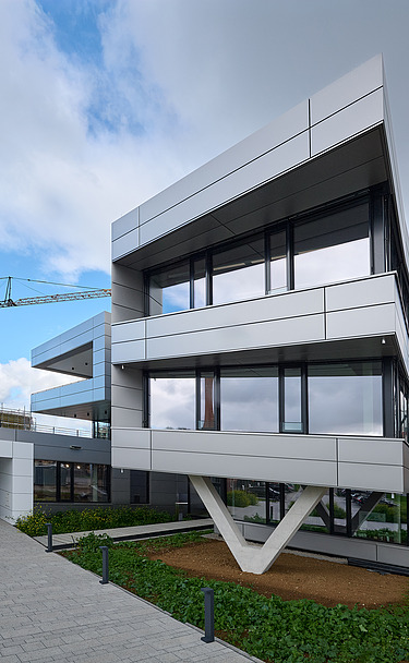 Foto Eingangsbereich Gebäude mit gekrümmter Fassade und V-förmiger Stütze