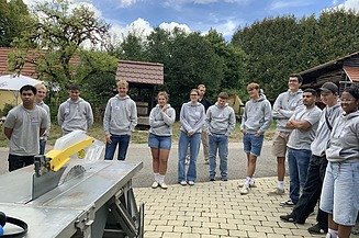 Auszubildende stehen bei der Einweisung um die Tischkreissäge