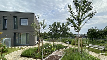 Foto des Garten mit Parkbank und Gebäude im Hintergrund