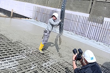 1 Frau betoniert eine Bodenplatte und wird dabei fotografiert für ein Shooting