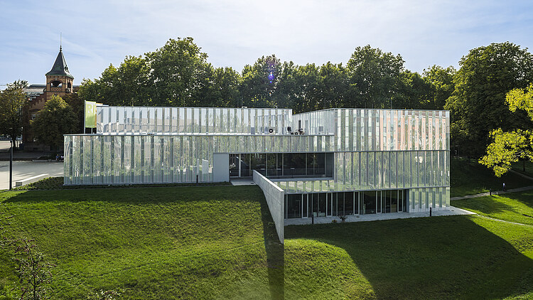 Foto eines Gebäudes mit Glasfassade auf einer grünen Wiese
