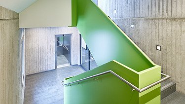 Foto Treppenhaus mit Sichtbeton und grüner Verkleidung am Treppenlauf