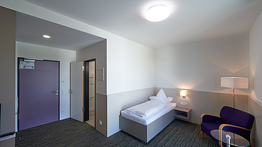 Foto Gästezimmer von Innen mit Bett, Sessel und Tisch