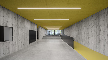 Foto Innenbereich Gang in Sichtbeton und gelber Decke mit Beleuchtung