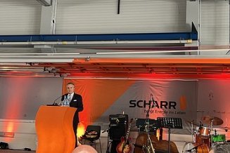1 Mann steht auf einer Bühne und hält eine Rede