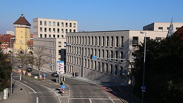 Foto von Gebäude von weiter weg mit Straße und blauem Himmel