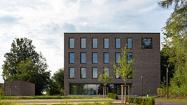 Foto Gebäude außen mit Eingangsbereich und Parkplätzen