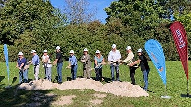 Foto von Menschen, die mit einem Spatenstich Sand von einem Hügel werffen