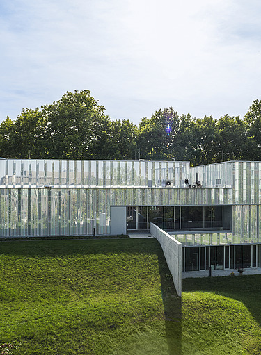 Foto eines Gebäudes mit Glasfassade auf einer grünen Wiese