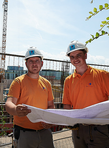 Foto von 2 jungen Männer, die einen Plan anschauen