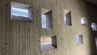 Foto von Sichtbetonwand mit konisch zugeschnittenen Lichtfenstern